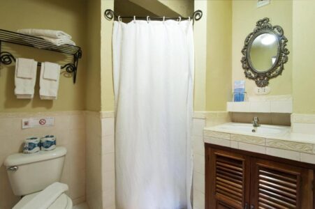 Hotel bathroom with white porcelain toilet, sink, and framed mirror