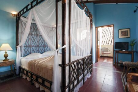 Four-poster bed with white canopy in a blue-walled room